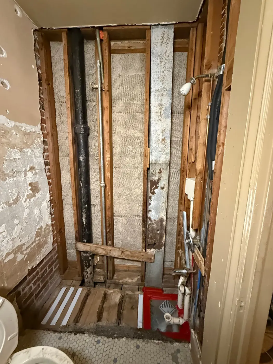 Bathroom stripped to the studs after asbestos plaster and tile demolition under containment in a Denver home